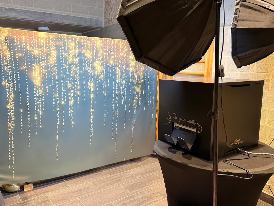 Photobooth met uitgifte van de prints naast een backdrop met gouden lichtjes en twee softboxen